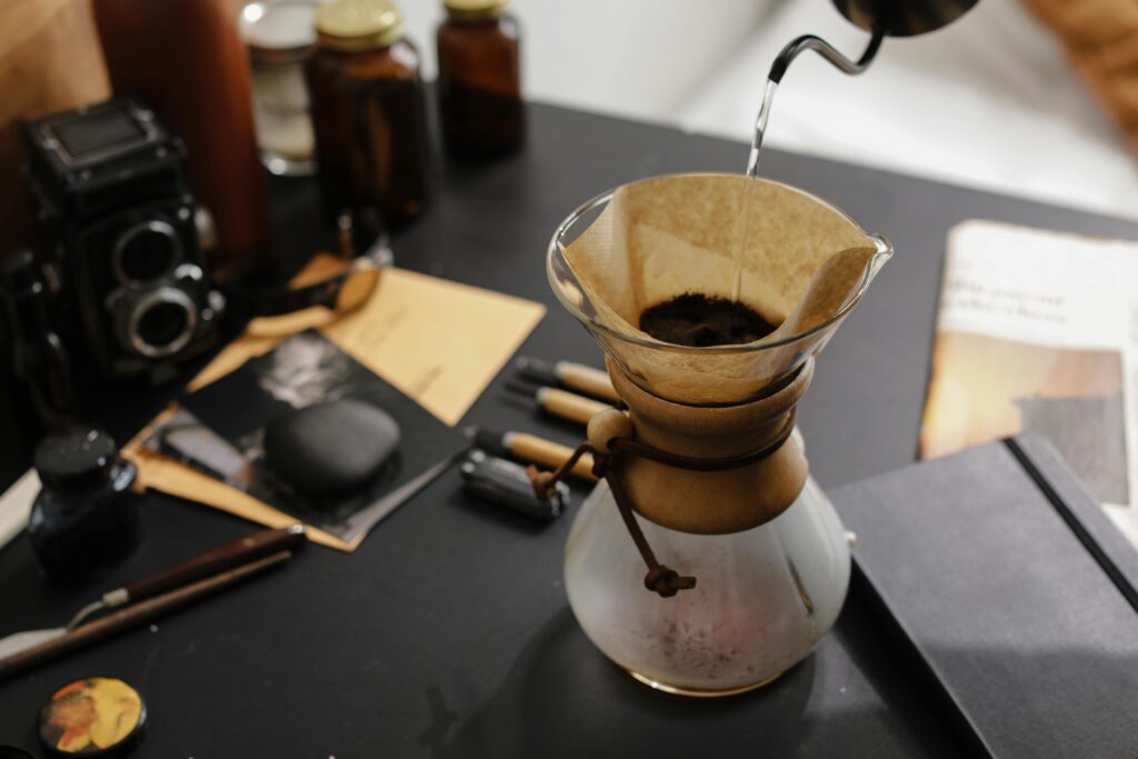 Person Pouring Liquid in a Clear Glass with Coffee Filter